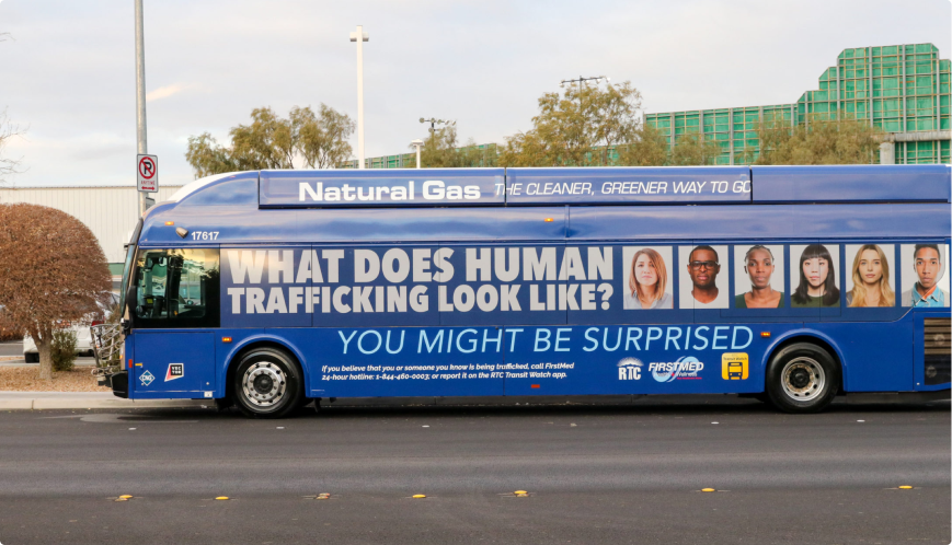 Human Trafficking Awareness A blue city bus with a large ad reading What does human trafficking look like? You might be surprised above photos of diverse people, promoting awareness and a human trafficking hotline.